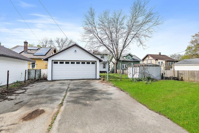 view of front of house with fence, a detached garage, an outdoor structure, and a front lawn