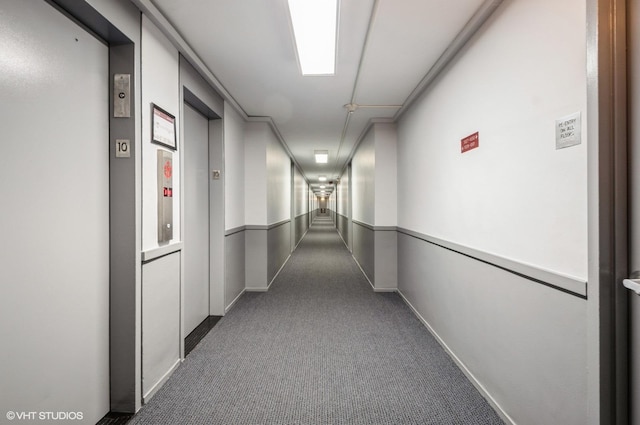 corridor featuring carpet flooring, elevator, and baseboards