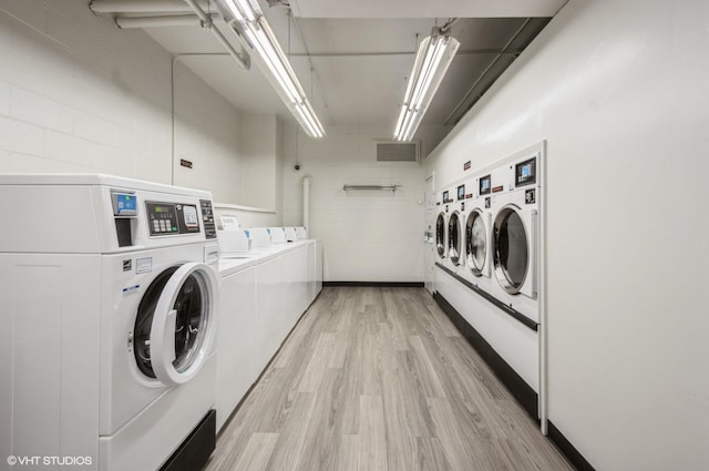 shared laundry area with washing machine and clothes dryer, concrete block wall, visible vents, and light wood-style flooring