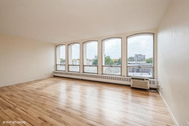 empty room with radiator heating unit, baseboards, and light wood finished floors