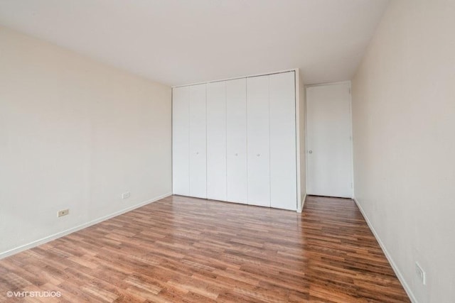 unfurnished bedroom featuring a closet, baseboards, and wood finished floors