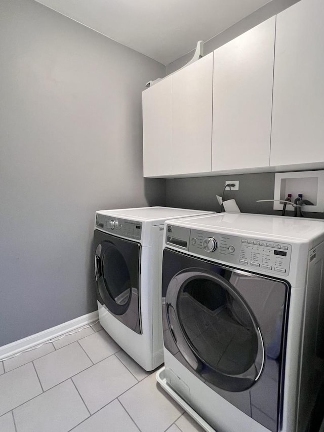 washroom with baseboards, cabinet space, light tile patterned floors, and washing machine and clothes dryer