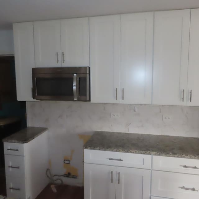 457 N Cambridge Dr Unit 457, Palatine, IL 60067 - kitchen featuring white cabinets, stainless steel microwave, light stone counters, and decorative backsplash