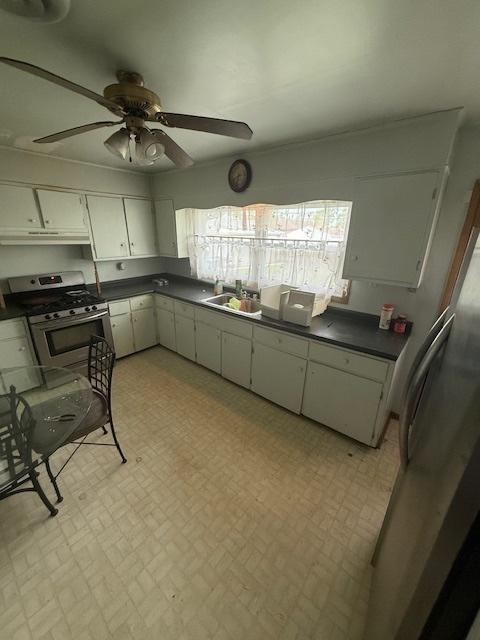 1304 Price Ave, Calumet City, IL 60409 - kitchen featuring dark countertops, a sink, stainless steel appliances, a ceiling fan, and white cabinetry