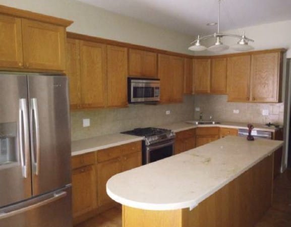 5217 S Ingleside Ave, Chicago, IL 60615 - kitchen featuring a kitchen island, brown cabinets, tasteful backsplash, a sink, and appliances with stainless steel finishes
