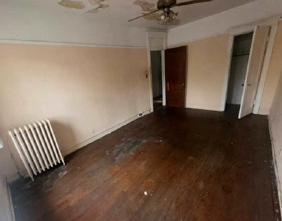 5217 S Ingleside Ave, Chicago, IL 60615 - unfurnished bedroom featuring radiator heating unit, baseboards, ceiling fan, and wood finished floors