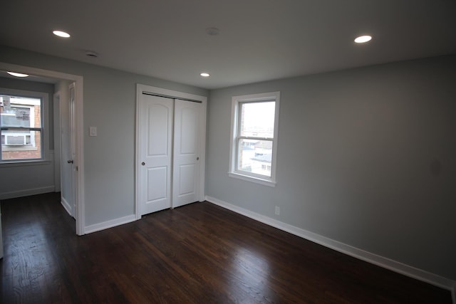 unfurnished bedroom with baseboards, dark wood finished floors, and multiple windows