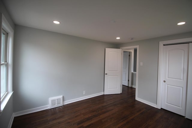 unfurnished bedroom featuring visible vents, a closet, baseboards, recessed lighting, and dark wood finished floors