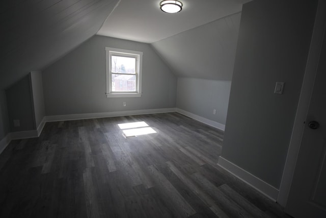 additional living space with baseboards, vaulted ceiling, and dark wood-style floors