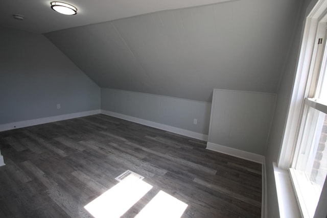 additional living space with dark wood-type flooring, baseboards, and lofted ceiling