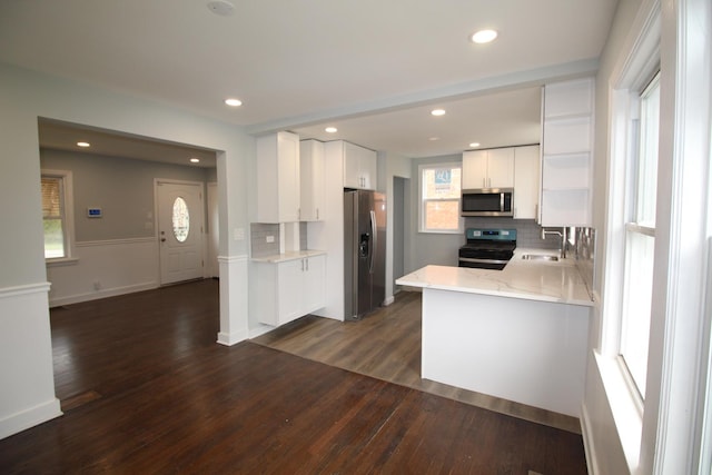 kitchen with appliances with stainless steel finishes, decorative backsplash, a sink, and dark wood-type flooring