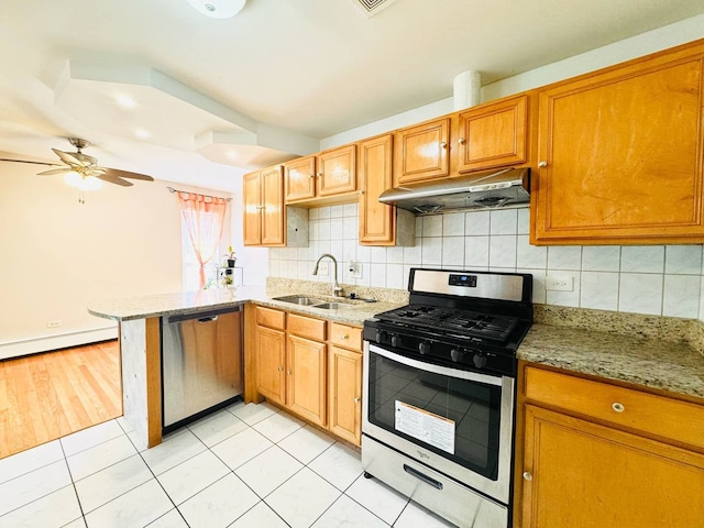 kitchen featuring appliances with stainless steel finishes, a sink, a baseboard heating unit, a peninsula, and under cabinet range hood
