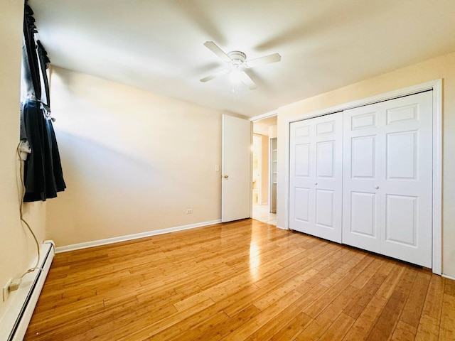 unfurnished bedroom featuring ceiling fan, light wood-style floors, baseboards, a baseboard heating unit, and a closet
