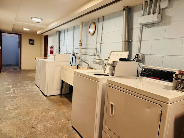 community laundry room featuring washer and dryer and concrete block wall