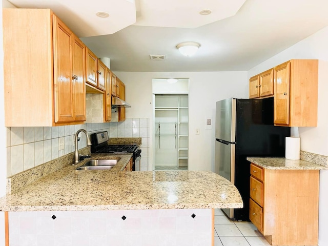 kitchen featuring light stone countertops, a sink, a peninsula, under cabinet range hood, and stainless steel appliances