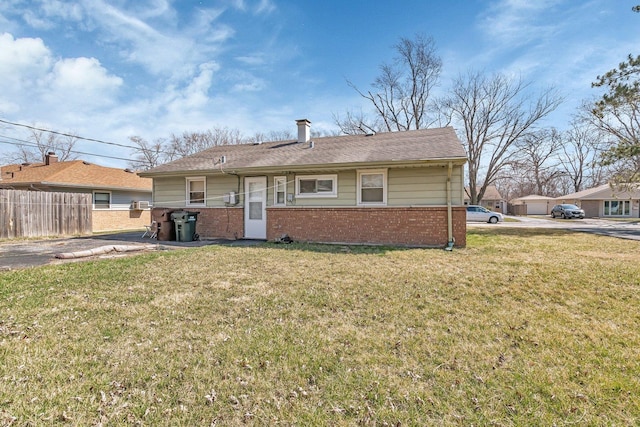 view of front facade with brick siding, fence, and a front yard