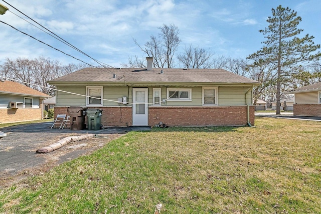 rear view of house with a lawn and brick siding