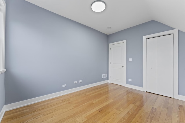 5052 W Huron St, Chicago, IL 60644 - unfurnished bedroom with baseboards, visible vents, light wood finished floors, and lofted ceiling