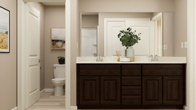 bathroom featuring double vanity, wood finished floors, a sink, baseboards, and toilet