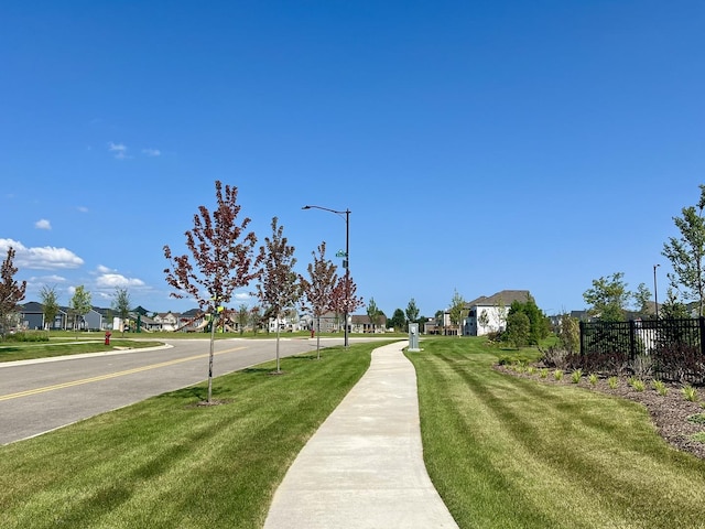 surrounding community featuring a lawn, fence, and a residential view