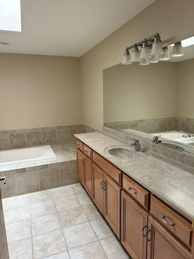 bathroom featuring a skylight, a bath, and vanity