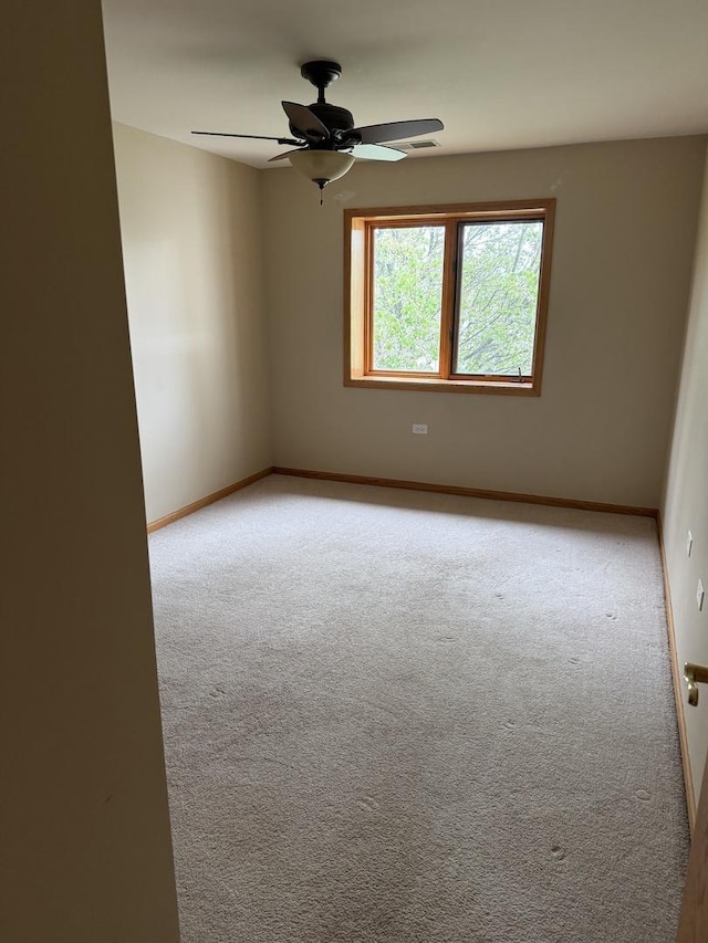 carpeted spare room with baseboards and a ceiling fan