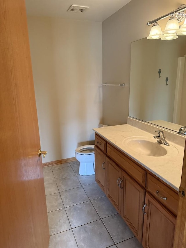 bathroom featuring visible vents, vanity, toilet, baseboards, and tile patterned floors