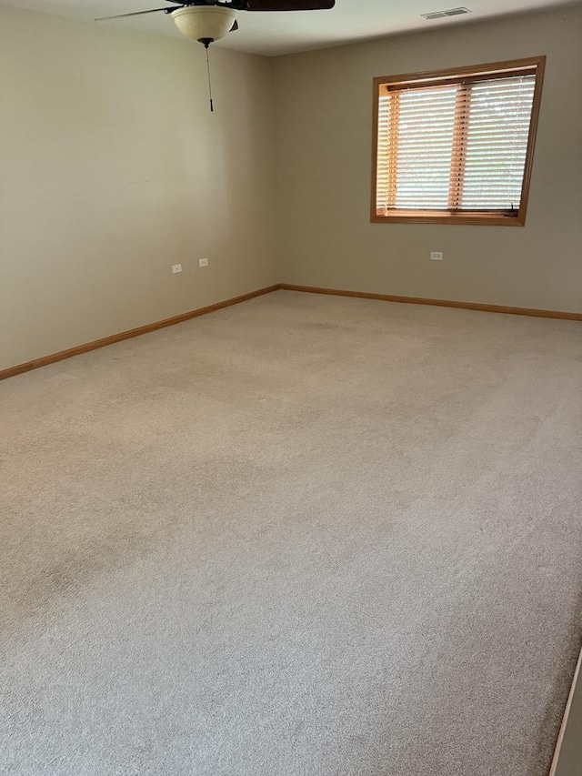 empty room with baseboards, ceiling fan, light carpet, and visible vents