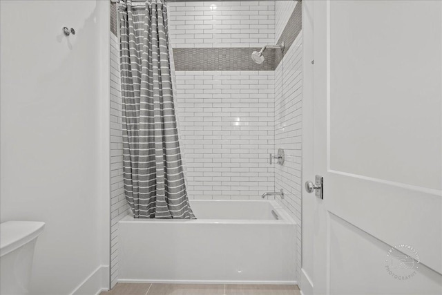 bathroom featuring shower / bathtub combination with curtain, toilet, and baseboards