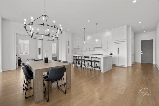 dining space with a chandelier, recessed lighting, light wood finished floors, and baseboards