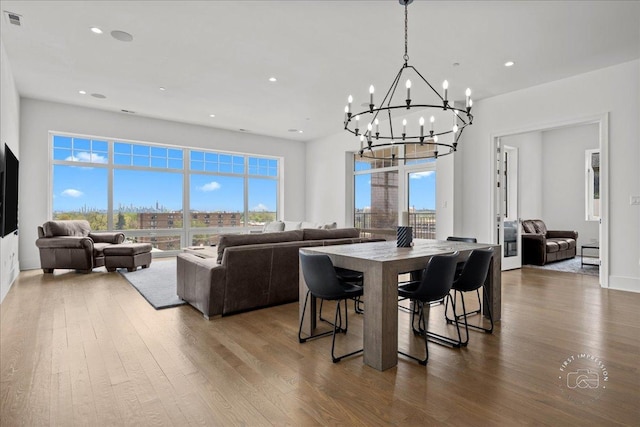 dining area with a chandelier, wood finished floors, healthy amount of natural light, and recessed lighting