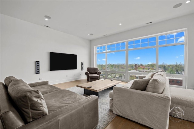 living area featuring healthy amount of natural light, wood finished floors, recessed lighting, and baseboards