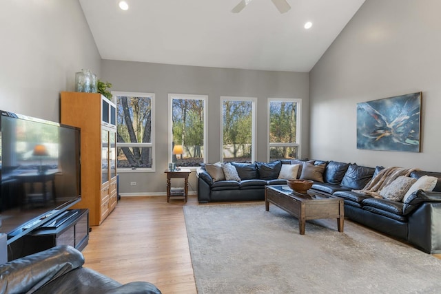 living room featuring baseboards, ceiling fan, high vaulted ceiling, recessed lighting, and light wood-style flooring