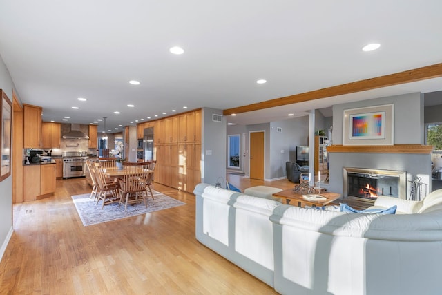 living room with visible vents, a glass covered fireplace, baseboards, recessed lighting, and light wood-style flooring