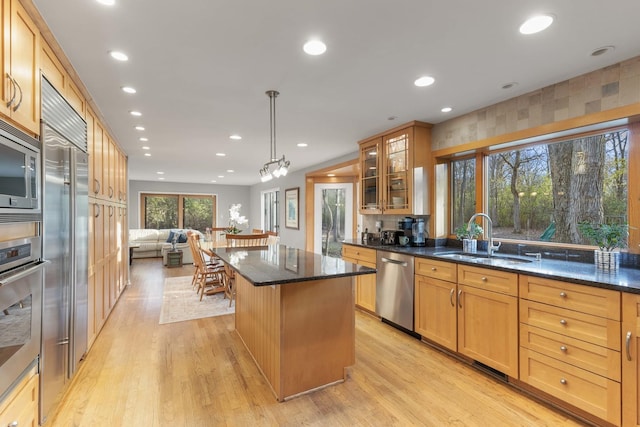 kitchen featuring a sink, built in appliances, a center island, light wood-type flooring, and glass insert cabinets