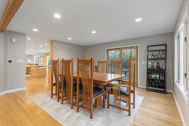 dining area with recessed lighting, baseboards, a bar, and light wood finished floors