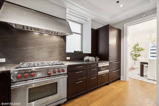 118 E Erie St Unit 19C, Chicago, IL 60611 - kitchen featuring high quality appliances, dark brown cabinets, light wood-style floors, wall chimney exhaust hood, and ornamental molding