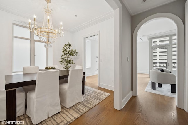 118 E Erie St Unit 19C, Chicago, IL 60611 - dining space featuring an inviting chandelier, arched walkways, baseboards, wood finished floors, and ornamental molding