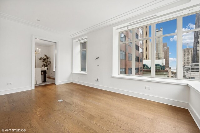 118 E Erie St Unit 19C, Chicago, IL 60611 - unfurnished room featuring crown molding, wood finished floors, baseboards, a city view, and a notable chandelier