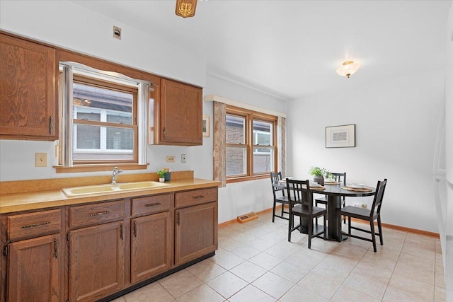 5532 W Lawrence Ave Unit 2S, Chicago, IL 60630 - kitchen with a sink, baseboards, brown cabinetry, light countertops, and light tile patterned floors
