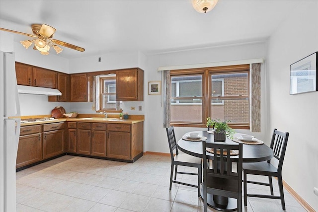 5532 W Lawrence Ave Unit 2S, Chicago, IL 60630 - kitchen featuring under cabinet range hood, white gas stovetop, light countertops, baseboards, and ceiling fan
