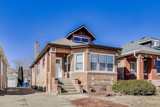 bungalow-style home with brick siding, driveway, and a chimney