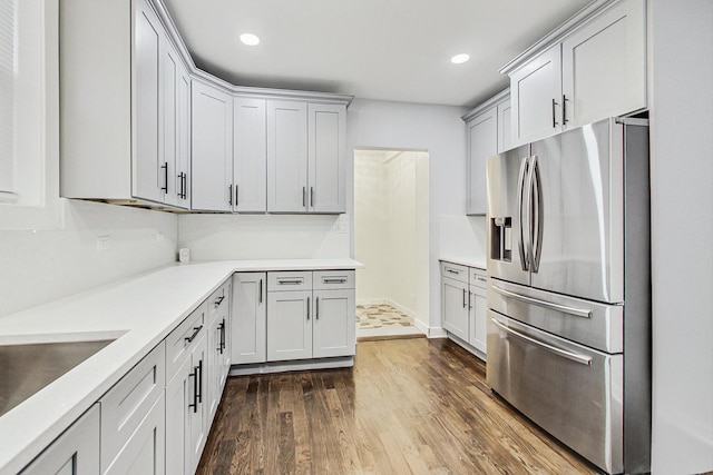 kitchen featuring dark wood-style floors, recessed lighting, light countertops, stainless steel fridge with ice dispenser, and a sink