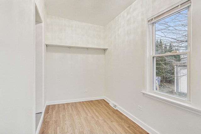 spare room featuring light wood-style floors, baseboards, and visible vents