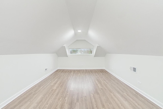 additional living space with visible vents, baseboards, lofted ceiling, and light wood finished floors
