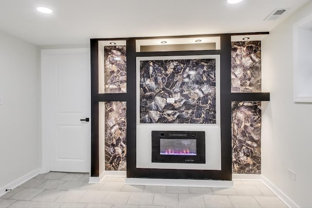 interior details featuring a glass covered fireplace, baseboards, recessed lighting, and visible vents