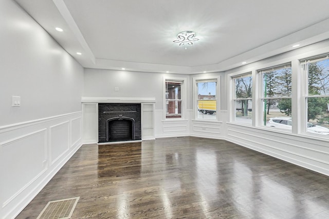 unfurnished living room with dark wood-style flooring, a fireplace, a decorative wall, recessed lighting, and visible vents