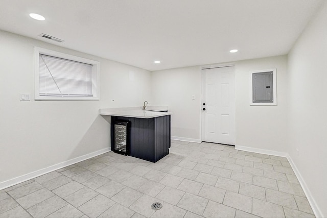 interior space featuring a sink, baseboards, wine cooler, visible vents, and electric panel