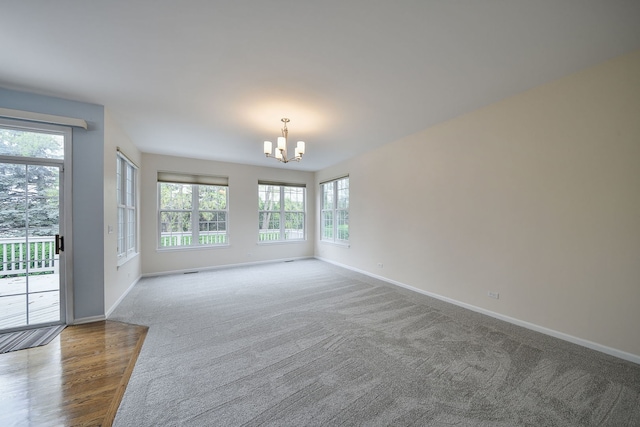 unfurnished room with baseboards, a notable chandelier, and a healthy amount of sunlight