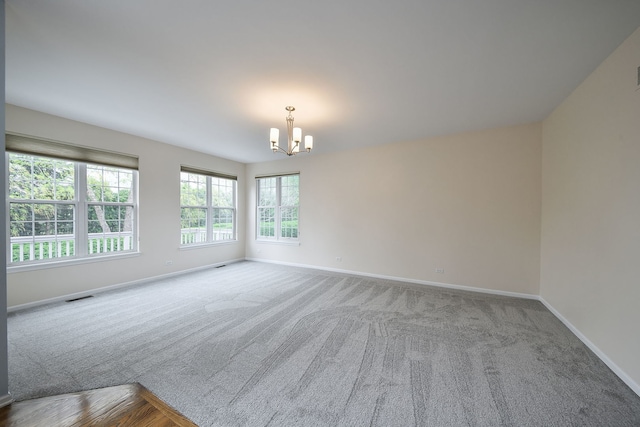 empty room featuring baseboards, carpet, a chandelier, and visible vents